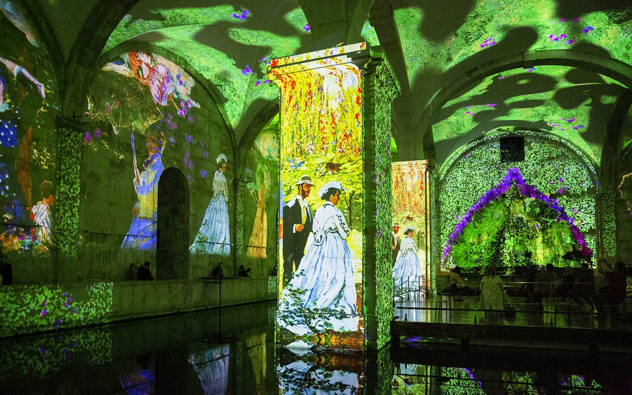 Monet and Klimt artworks projected in immersive exhibition space.