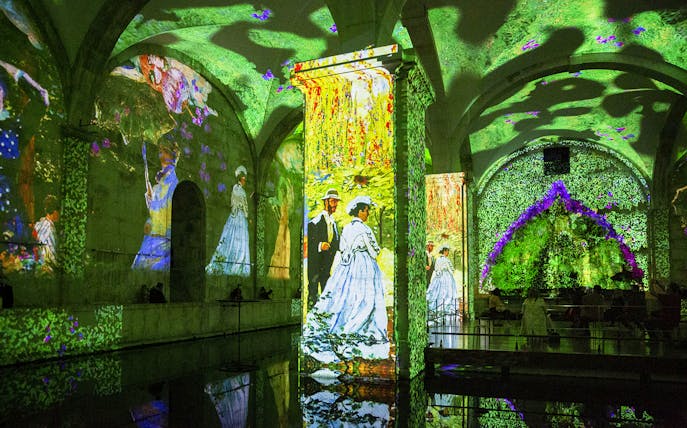 Monet and Klimt artworks projected in immersive exhibition space.