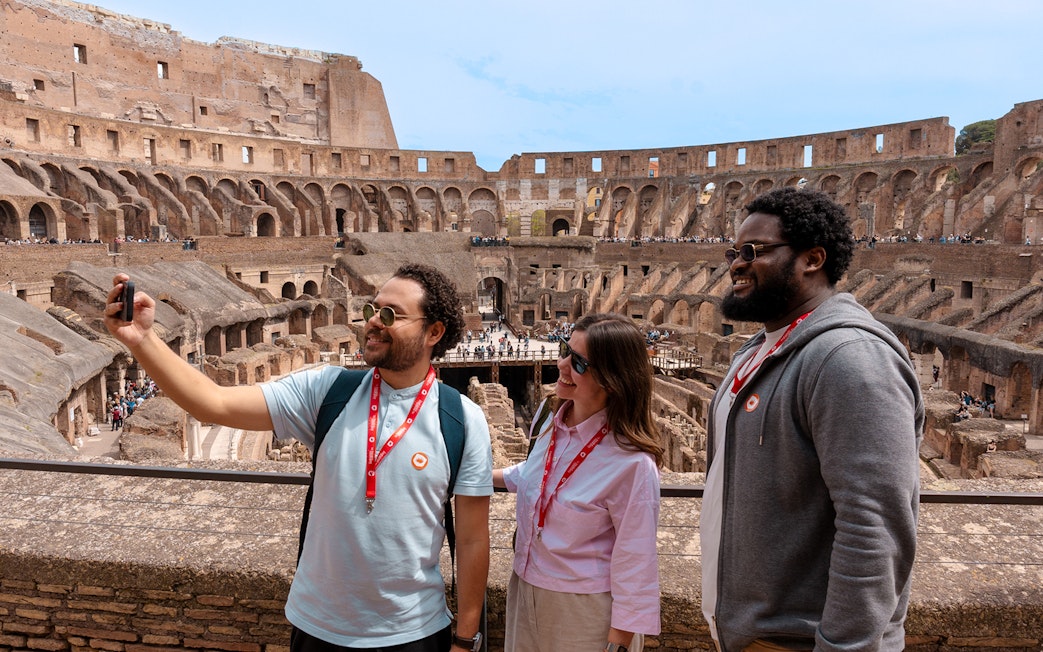 Tourists taking a selfie inside the historic Colosseum in Rome, Italy.