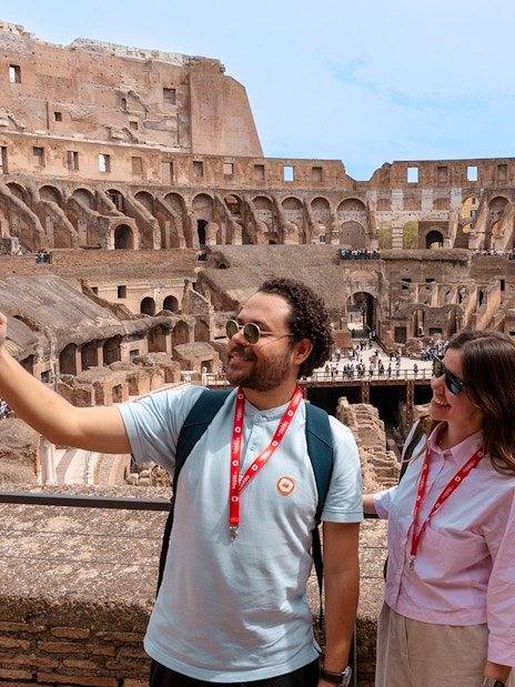 Tourists taking a selfie inside the historic Colosseum in Rome, Italy.