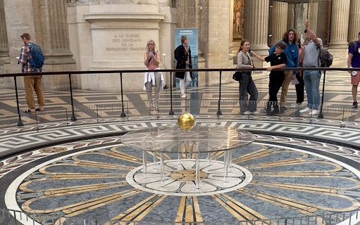 Foucault pendulum inside the Pantheon, Paris, with visitors observing the demonstration.