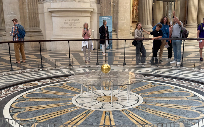 Foucault pendulum inside the Pantheon, Paris, with visitors observing the demonstration.