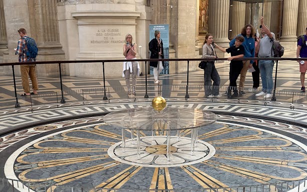 Foucault pendulum inside the Pantheon, Paris, with visitors observing the demonstration.