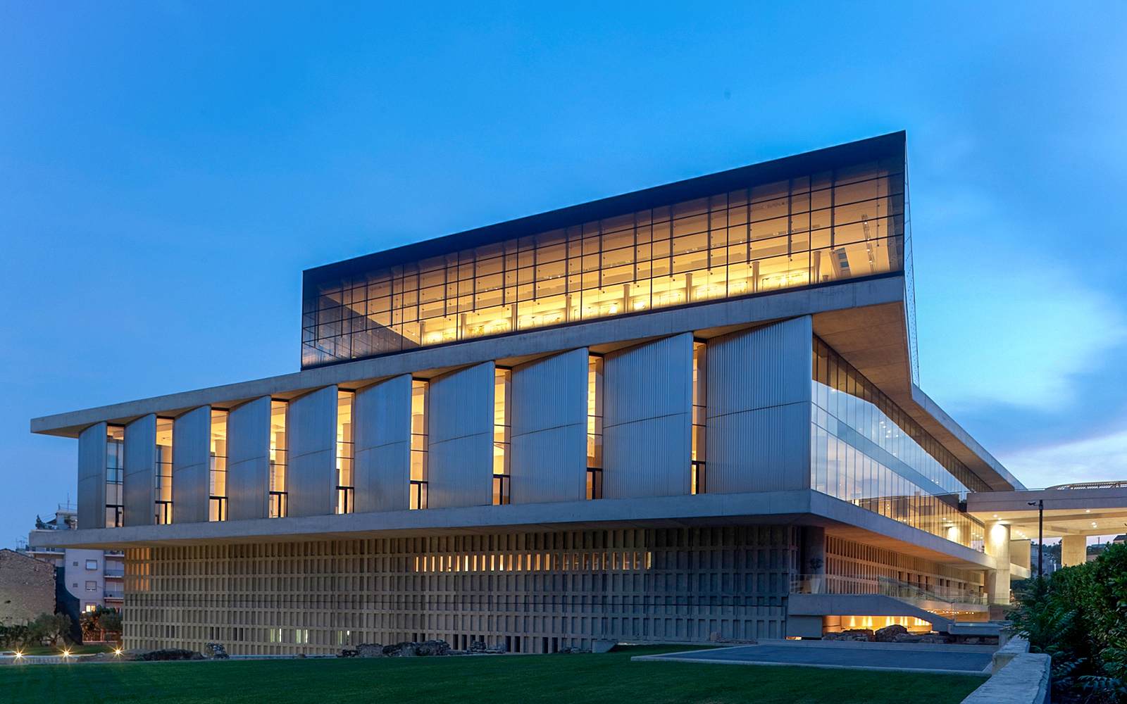 Acropolis Museum exterior illuminated during evening in Athens, Greece.