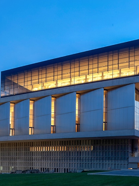 Acropolis Museum exterior illuminated during evening in Athens, Greece.