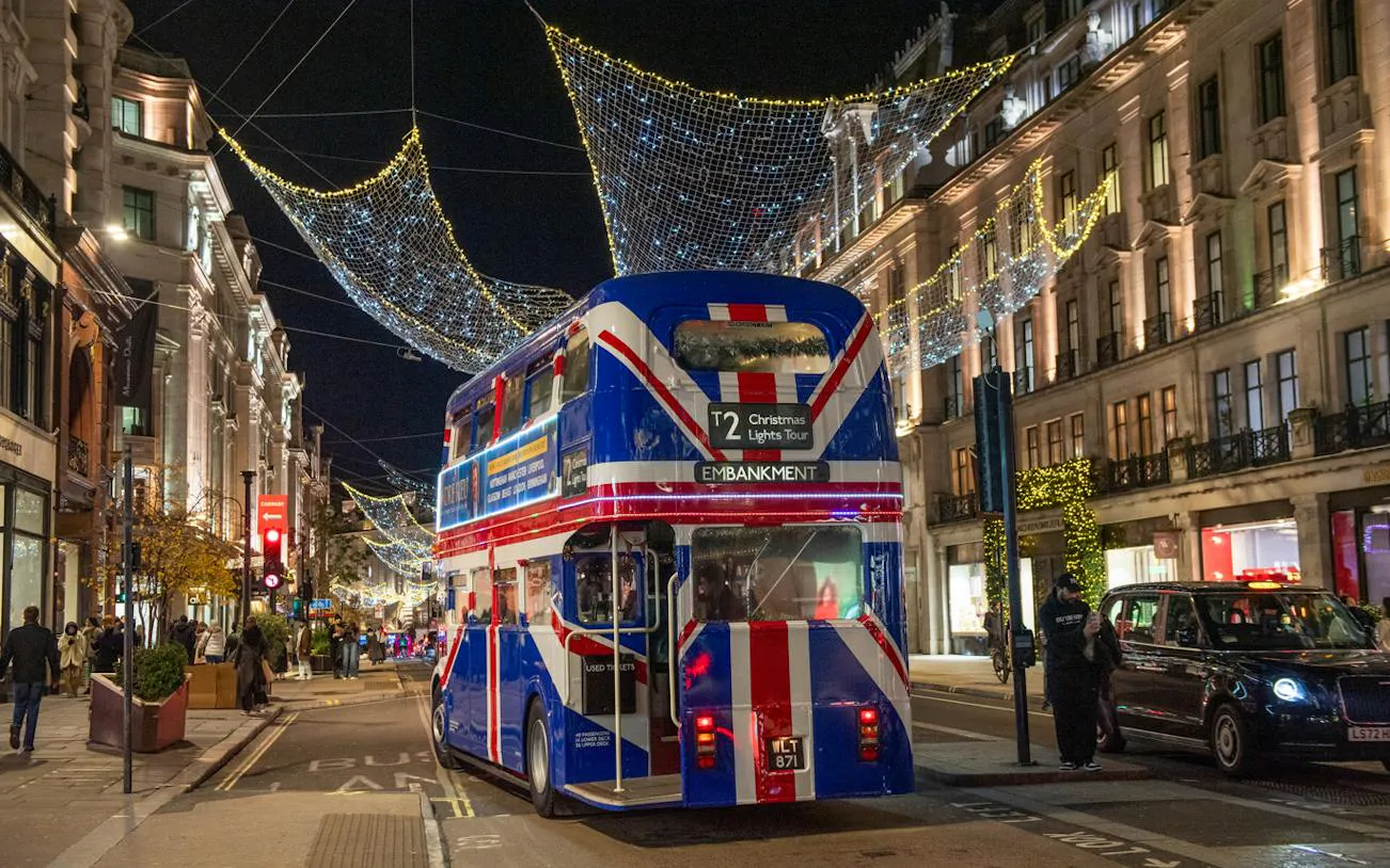 Double-decker bus on London street with Christmas lights overhead.