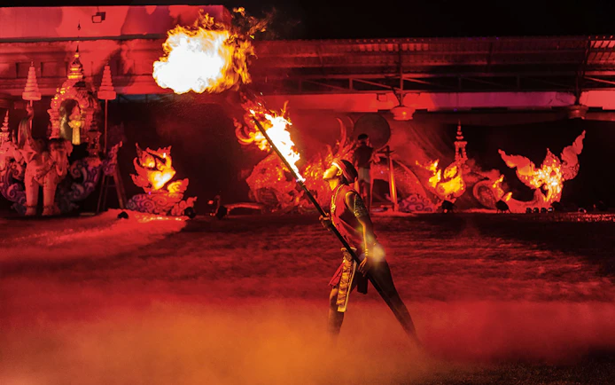Fire performer at Yeepeng Lanna Festival 2023 with traditional decorations in the background.