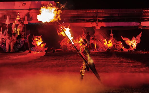 Fire performer at Yeepeng Lanna Festival 2023 with traditional decorations in the background.