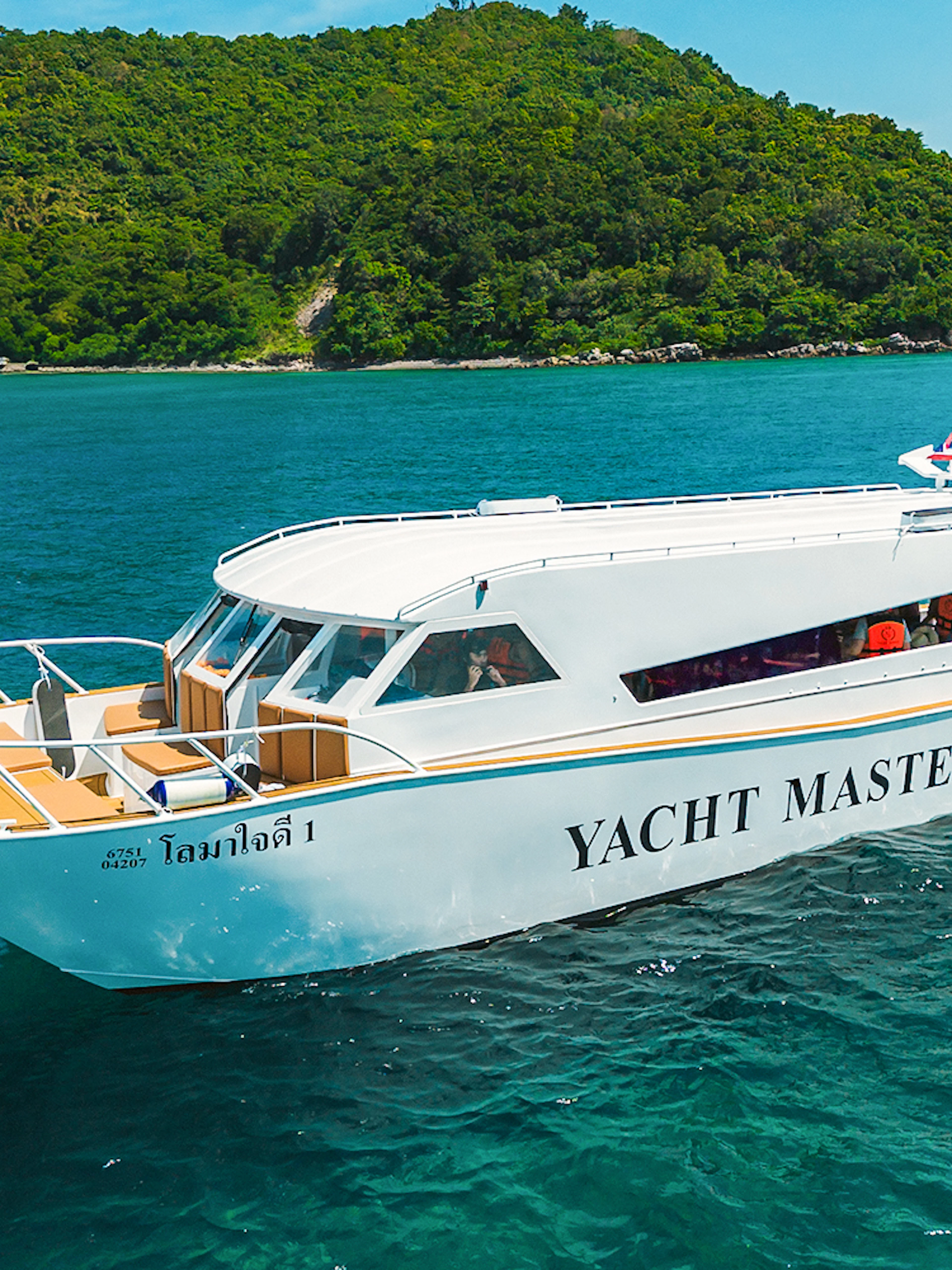 Premium speed catamaran cruising near lush green island.