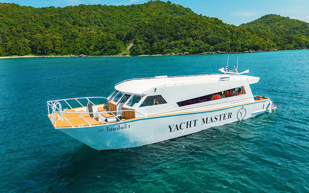 Premium speed catamaran cruising near lush green island.