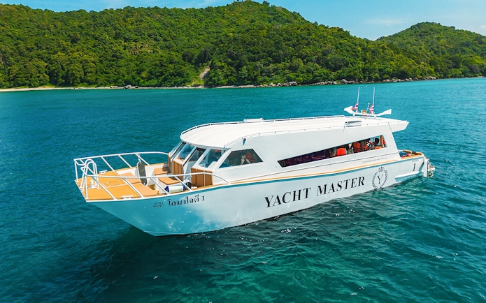 Premium speed catamaran cruising near lush green island.