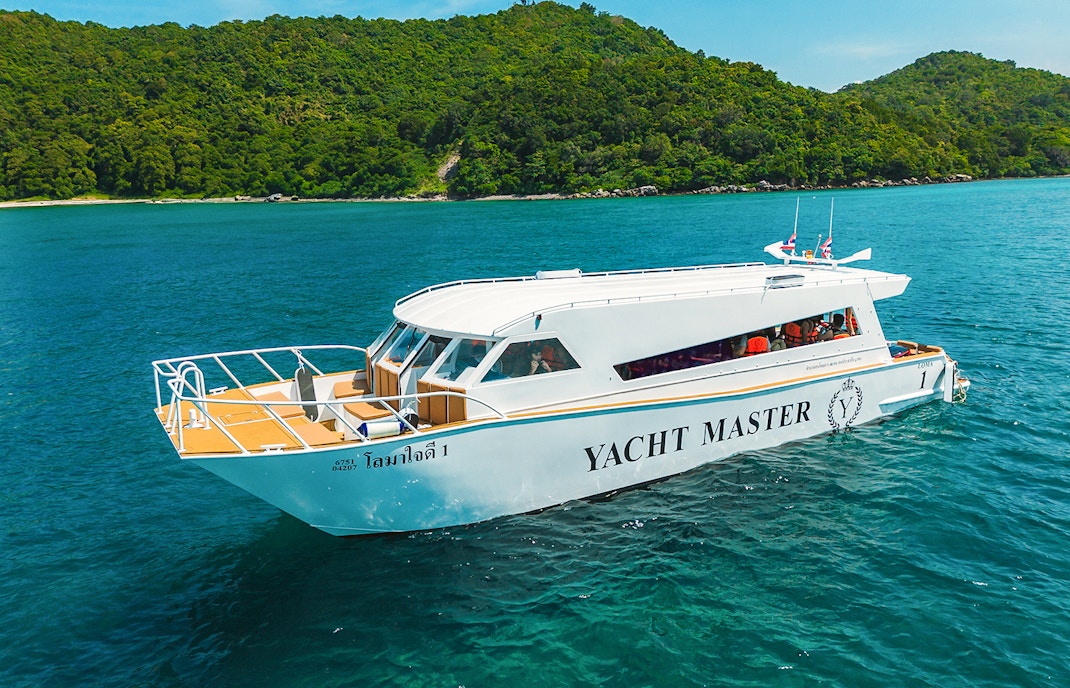 Premium speed catamaran cruising near lush green island.