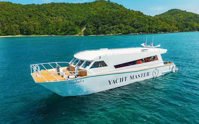 Premium speed catamaran cruising near lush green island.