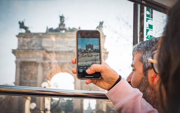 Person taking a photo of Arco della Pace from a tour bus in Milan.