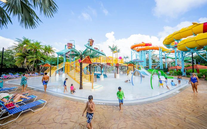 Children playing at the water playground in Adventure Island, Tampa with colorful slides and palm trees.