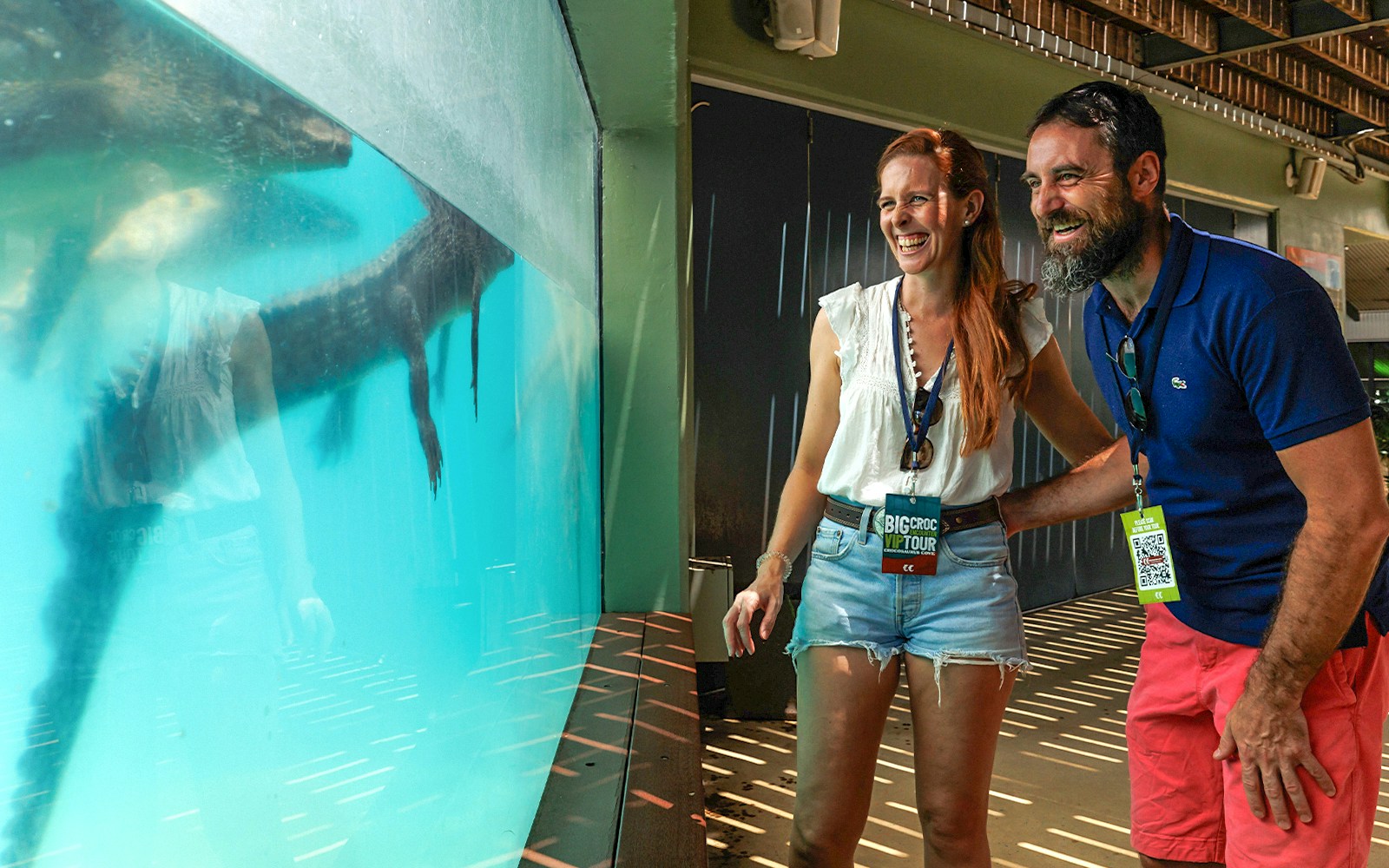 A couple laughs together while observing a massive crocodile swimming in the underwater viewing area at Crocosaurus Cove, Darwin, Australia