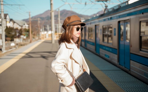 Woman waiting at Osaka metro station platform with train in background.