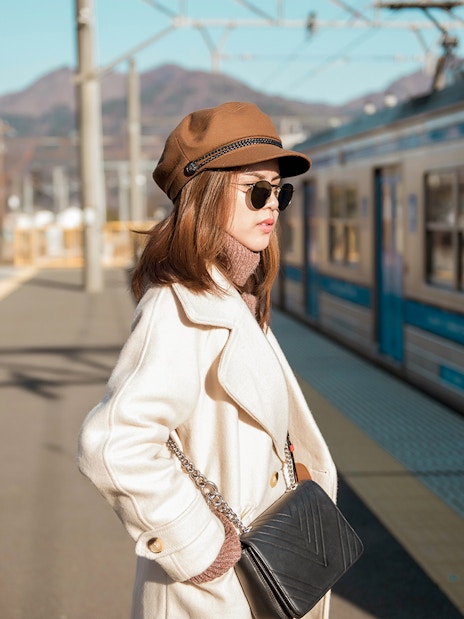 Woman waiting at Osaka metro station platform with train in background.