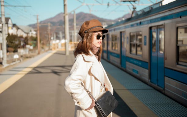 Woman waiting at Osaka metro station platform with train in background.