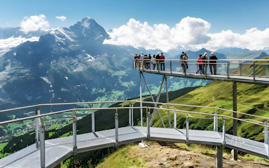 Tourists on viewing platform at Grindelwald First with mountain views.