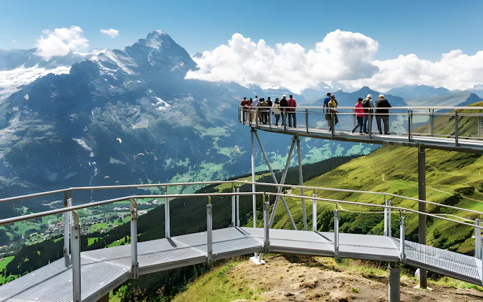 Tourists on viewing platform at Grindelwald First with mountain views.