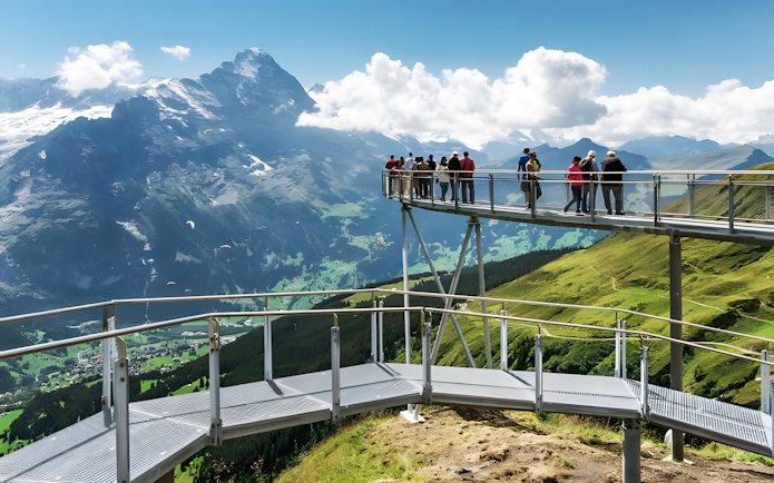 Tourists on viewing platform at Grindelwald First with mountain views.