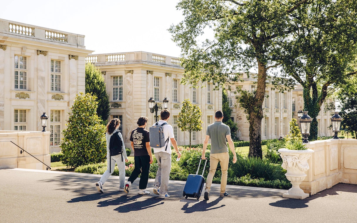 Visitors walking through Puy du Fou, France, near a grand building.