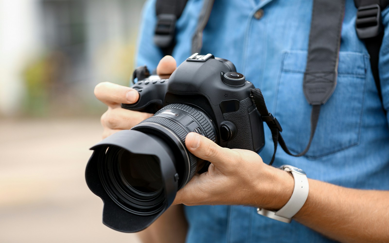 Man holding a DSLR camera, preparing for photography.