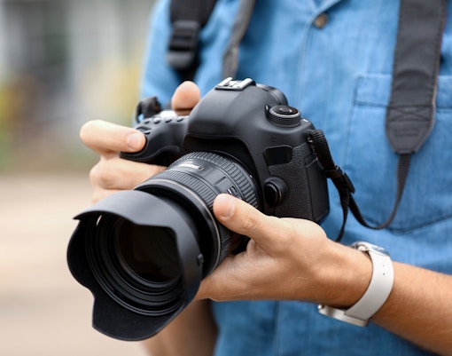 Man holding a DSLR camera, preparing for photography.