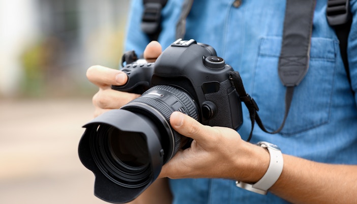 Man holding a DSLR camera, preparing for photography.