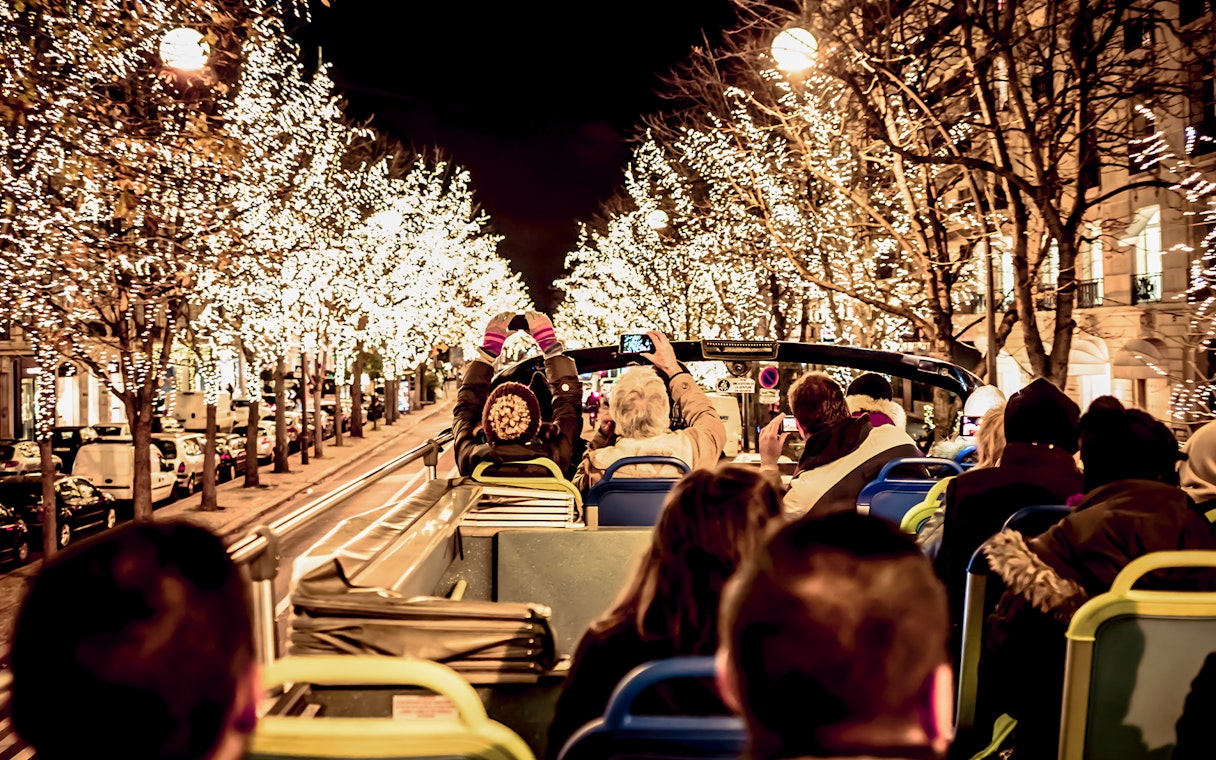 Tourists on open-top bus viewing Christmas lights in Paris.
