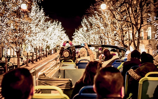 Tourists on open-top bus viewing Christmas lights in Paris.