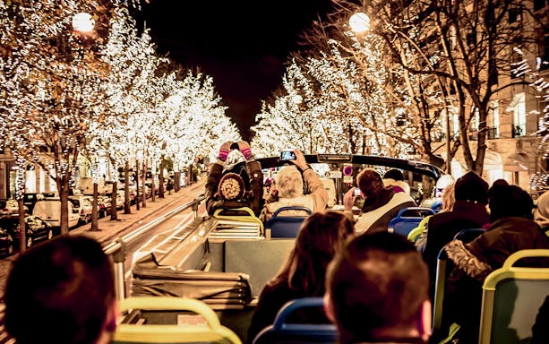 Tourists on open-top bus viewing Christmas lights in Paris.