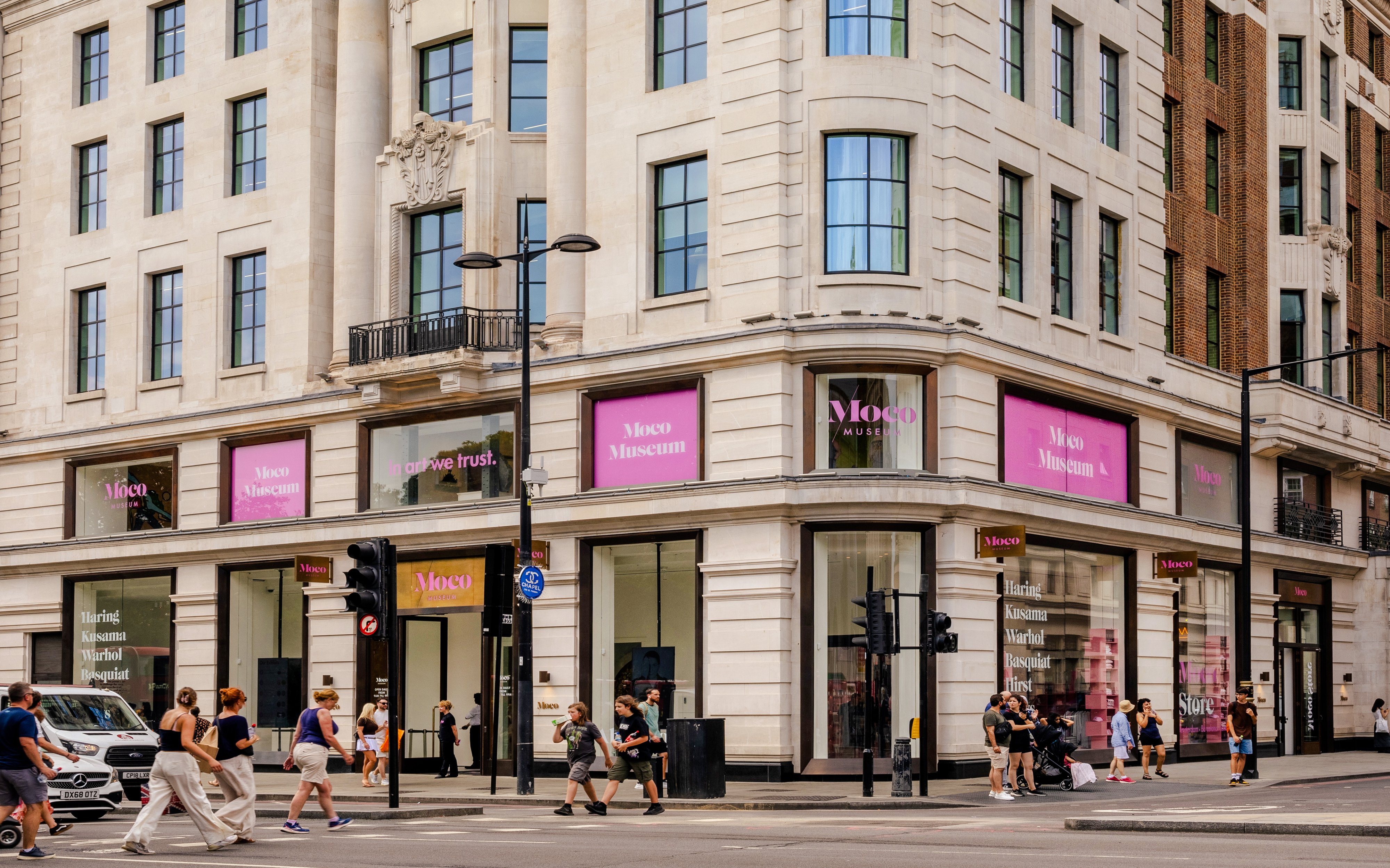 Exteriors of Moco Museum London with people walking by on a busy street corner.