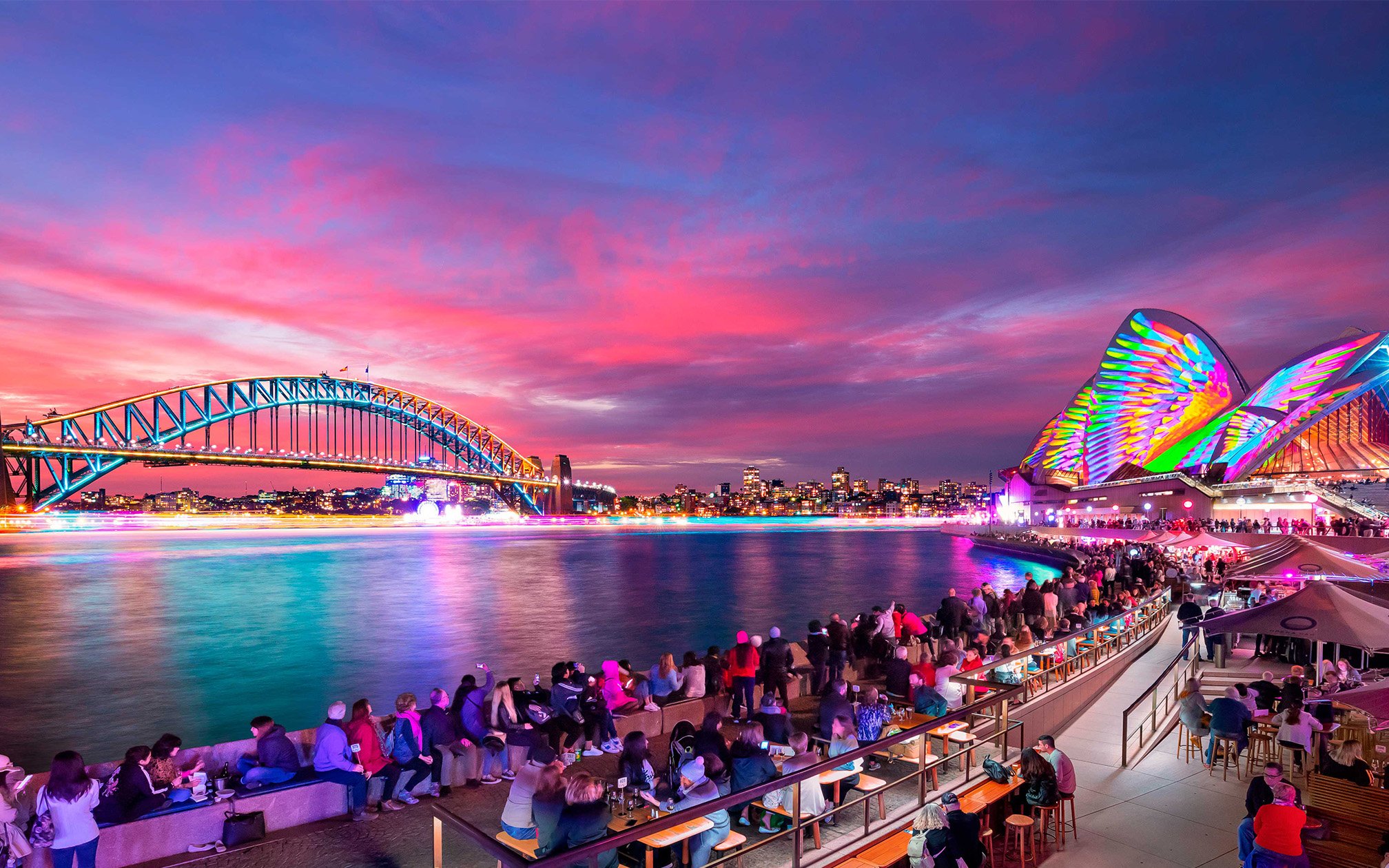 Sydney Harbour Bridge and Opera House illuminated during Vivid Sydney festival cruise.