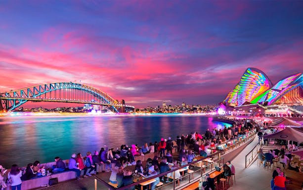 Sydney Harbour Bridge and Opera House illuminated during Vivid Sydney festival cruise.