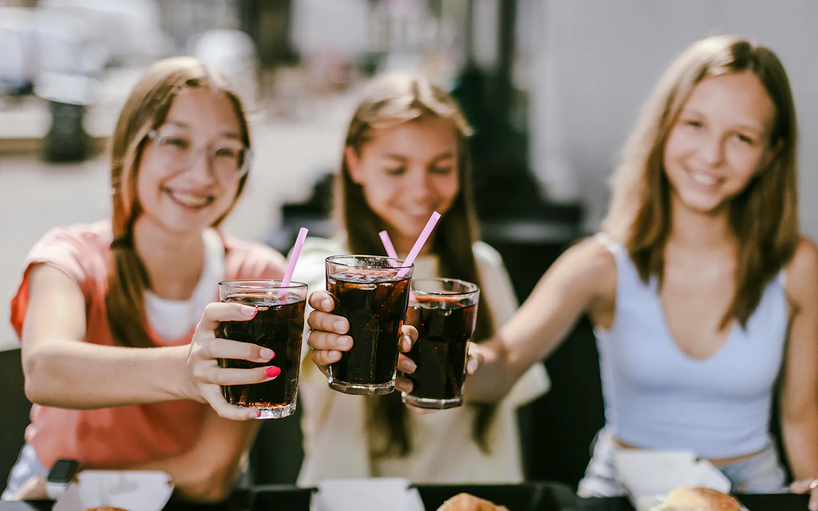 Group of friends toasting with soft drinks at an outdoor cafe.