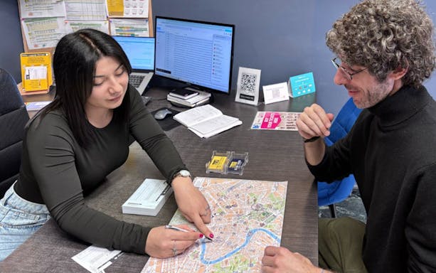 People discussing a map of Rome at a luggage storage service desk.