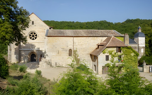 Beaulieu-en-Rouergue Abbey facade surrounded by greenery in France.