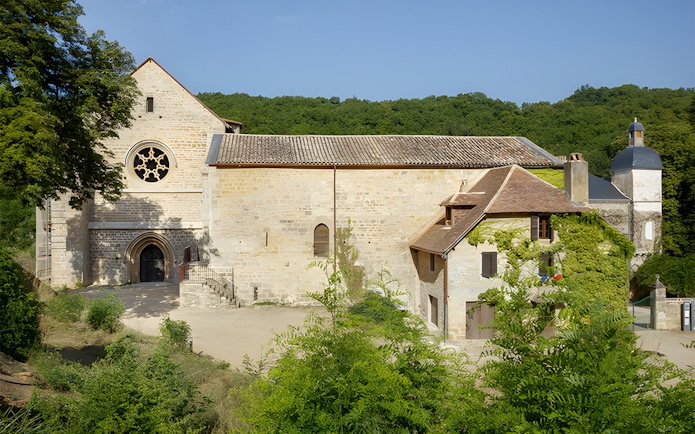Beaulieu-en-Rouergue Abbey facade surrounded by greenery in France.