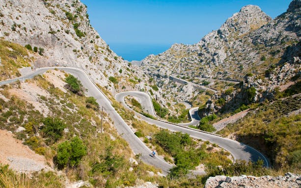 Winding mountain road in Mallorca with cyclist, part of sightseeing tour.