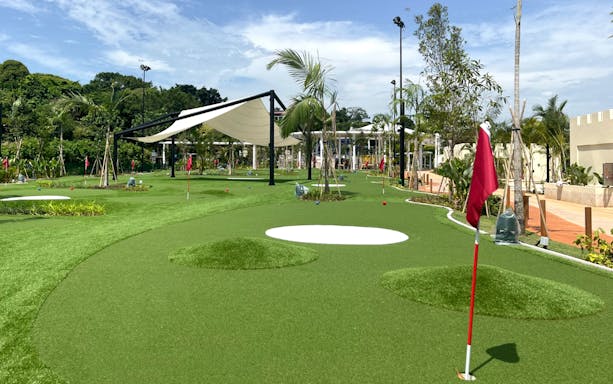Mini-golf course with red flags and lush greenery, UltraGolf General Ticket.