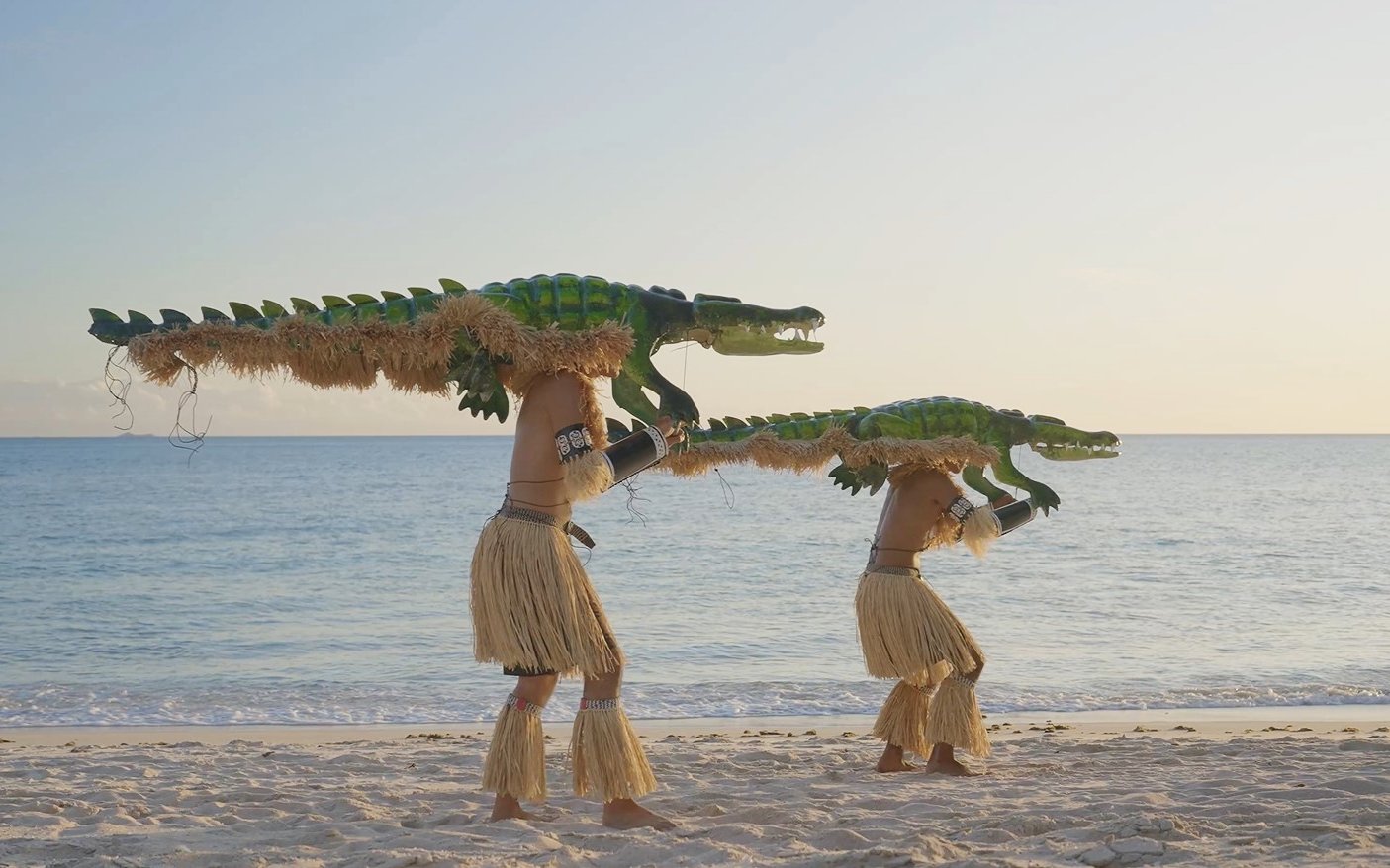 Performers with crocodile costumes on a beach, part of Croc! Lost Giants to Living Legends at Queensland Museum.