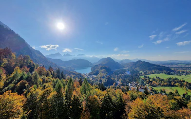 View of Bavarian landscape from Neuschwanstein and Hohenschwangau Castle, featuring forests and mountains.
