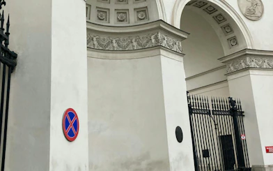 Warsaw city gate with ornate arch and no parking sign, part of self-guided mystery tour.