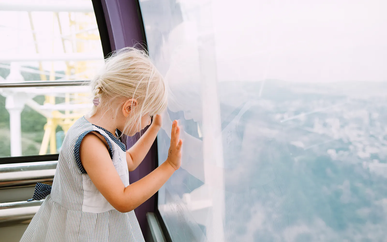 Little girl looking out from inside a Ferris wheel cabin.