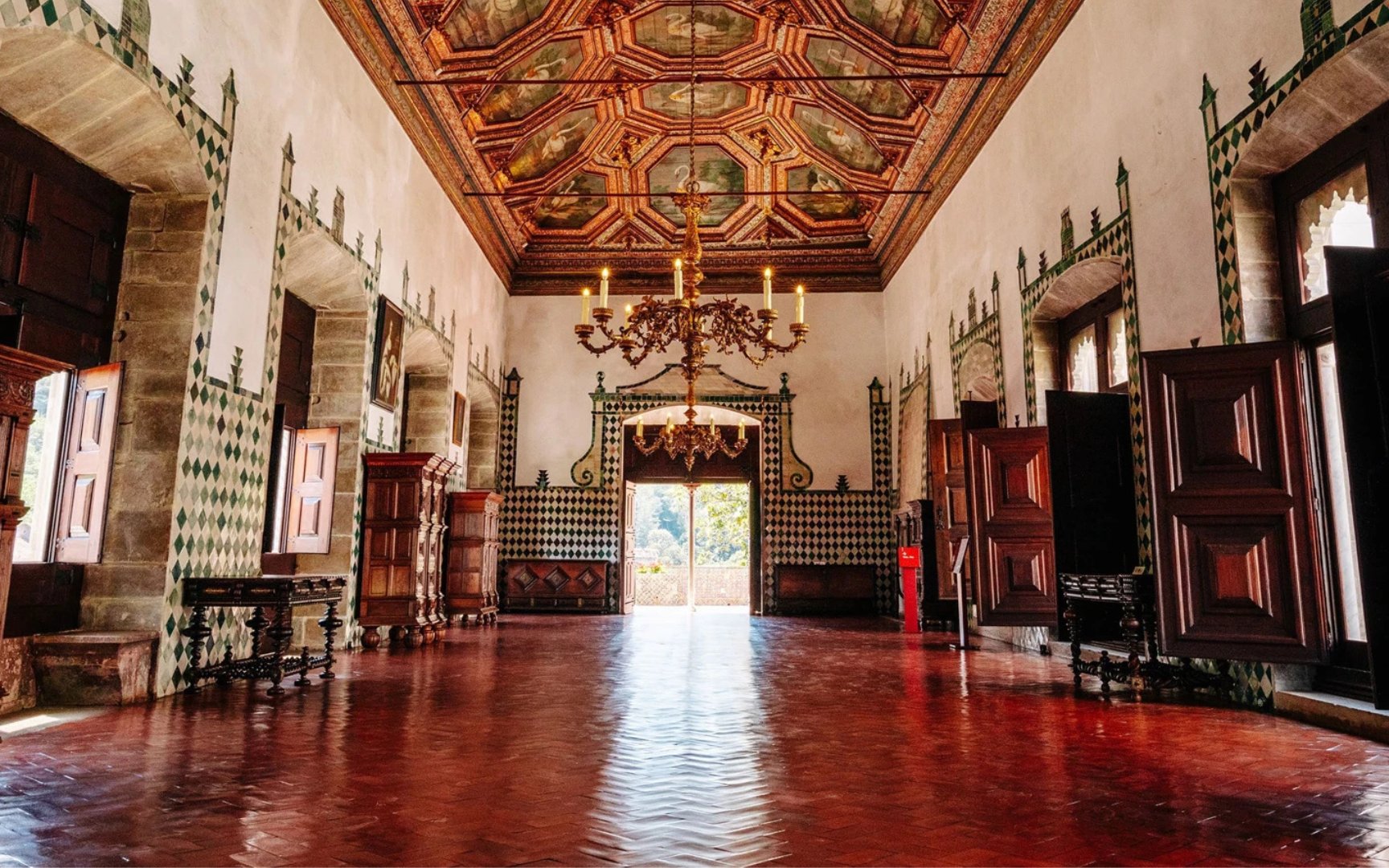 Interior of the National Palace of Sintra with ornate ceiling and open doors.