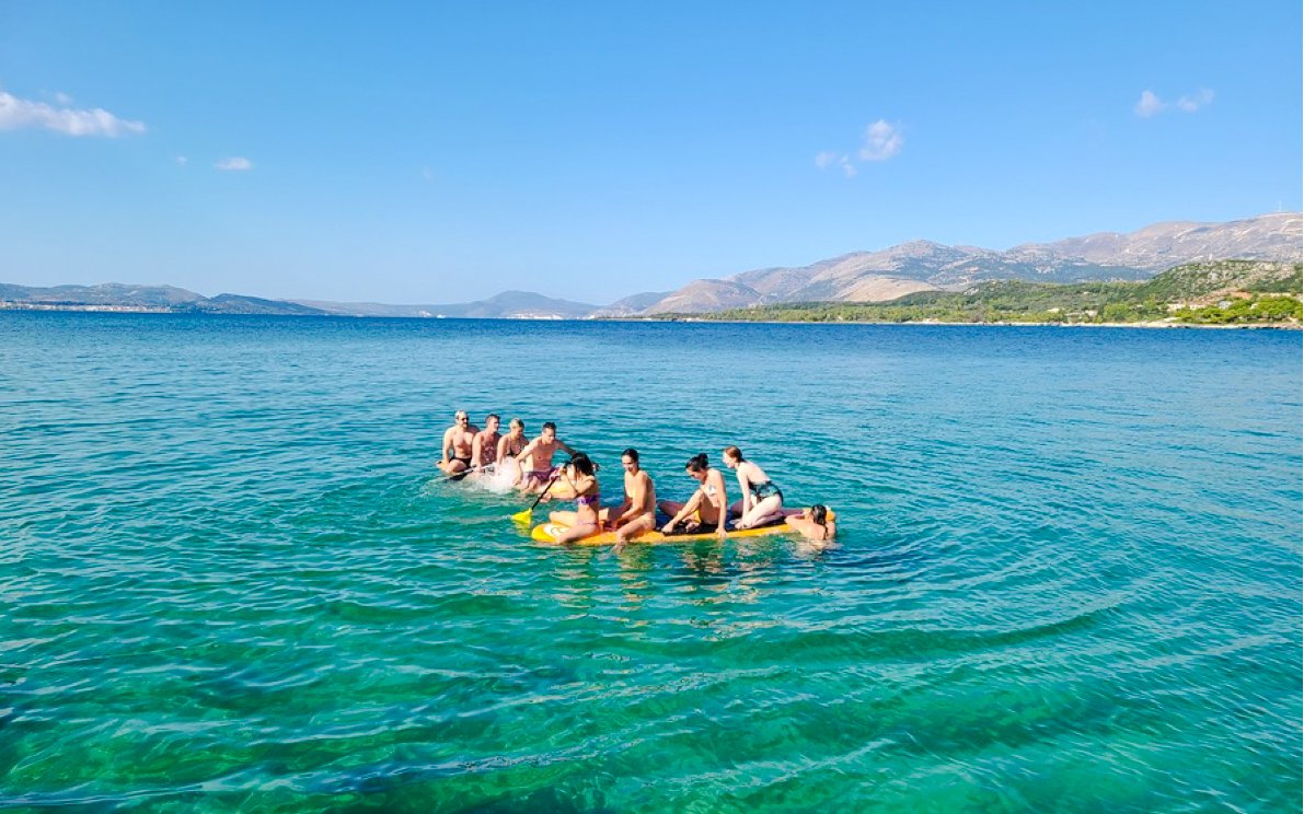 Group paddleboarding on clear waters in Kefalonia, Greece.