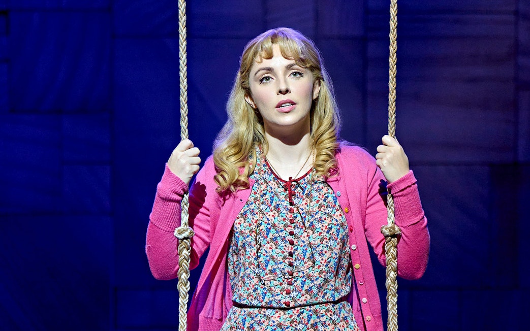 Performer on stage in Matilda The Musical holding a swing rope.