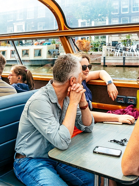 Tourists enjoying a canal cruise in Amsterdam, viewing city architecture.